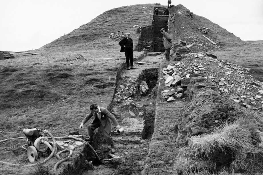 A black and white photograph of a group of people excavating Maeshowe chambered cairn