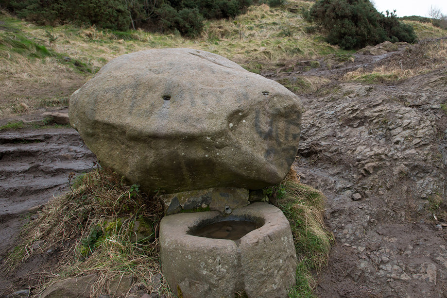 A small stone well near a stairways in a park
