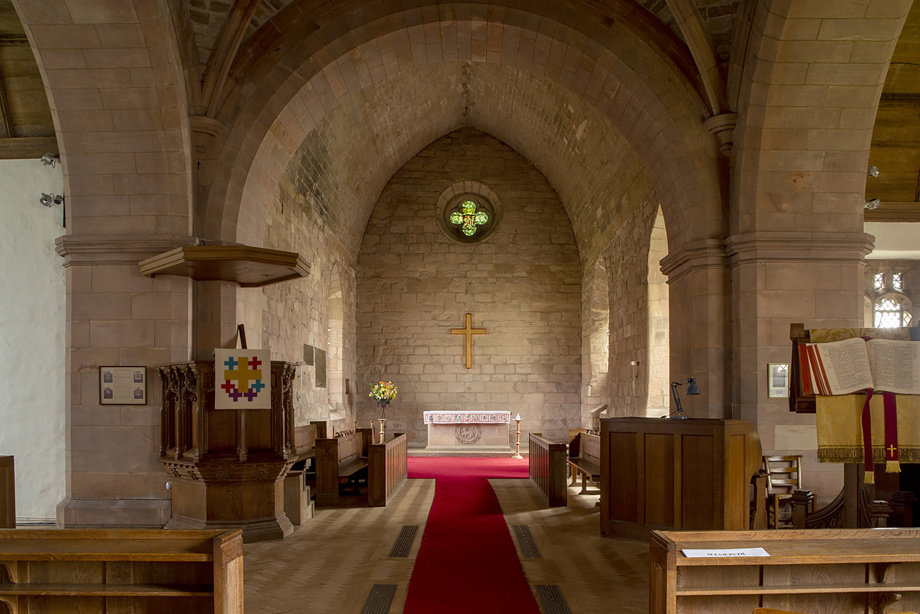 A small church room with carved ceiling and furniture, with a rug leading to an altar. Image reference number: DP_375230 