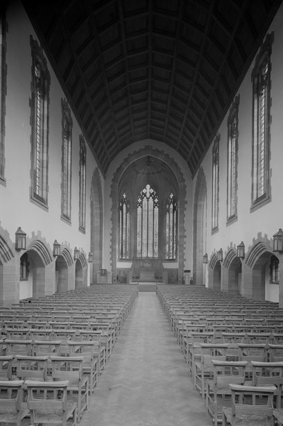 A long nave with a tall ceiling and many rows of wooden seats facing the chancel. Image reference number: SC_641605
