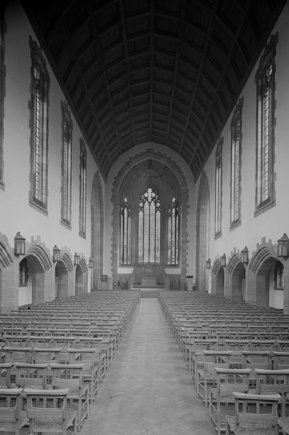 A long nave with a tall ceiling and many rows of wooden seats facing the chancel. Image reference number: SC_641605
