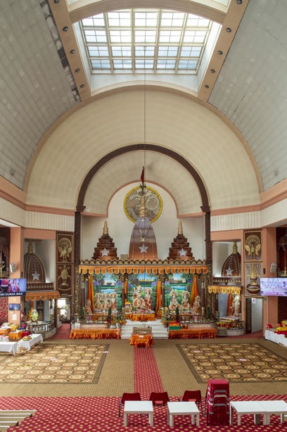 A room with a tall, circular ceiling, and prayer mats on the floor in front of an area of worship. Reference no: DP_367440 