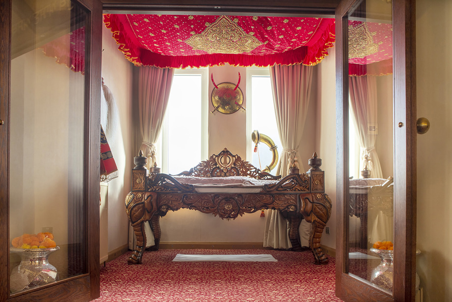 A golden embroidered red canopy hanging from the ceiling above an ornately carved wooden bench. Reference no: DP_374206