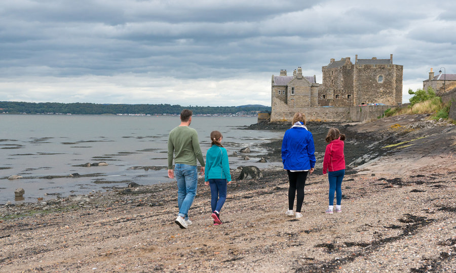 Family walking along beach towards Blackness Castle
