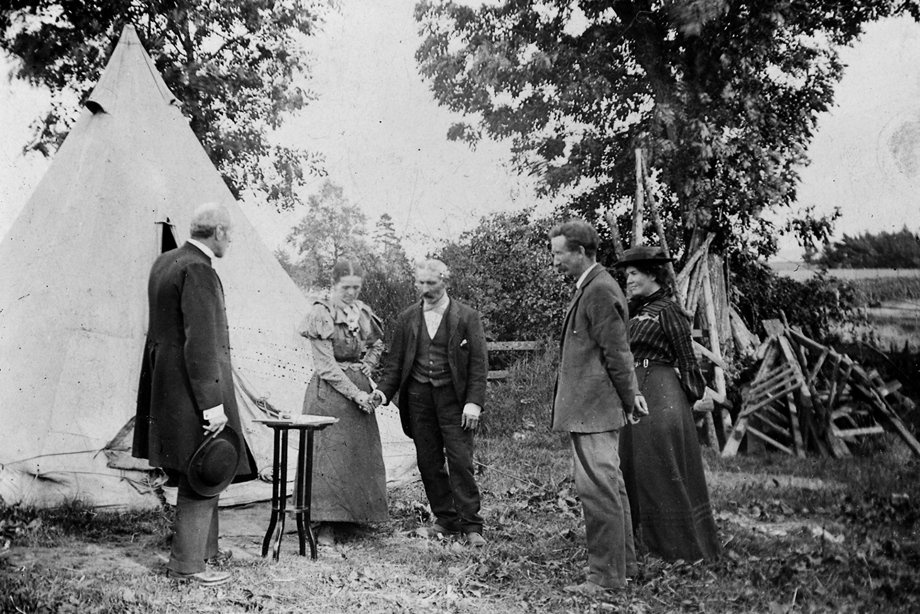 Two people being married with three witnesses outside a yurt