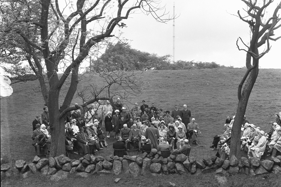 A preacher holds a Covenanters' conventicle and is surrounded by attendees in a field, beside a stone wall. Image reference number: 000-000-533-044-R