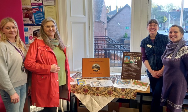A photo of the the book launch of ‘The Chronicles of Angus - Life through a Lens’ at Angus Alive Kirriemuir Library. Four people smiling at the camera are in the photo presenting the book.