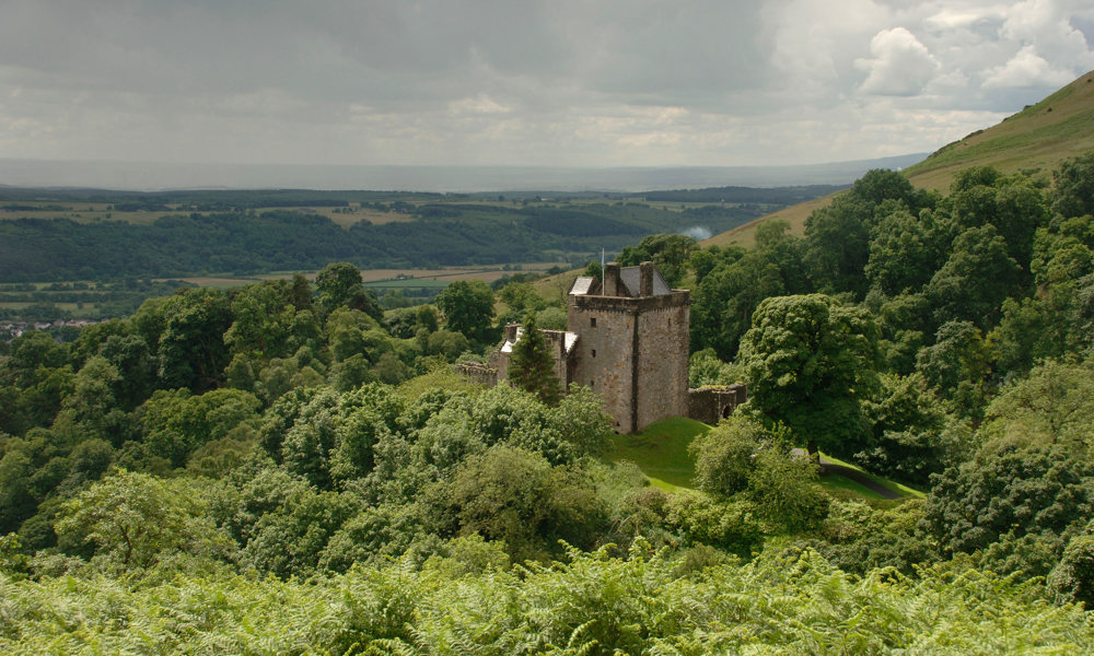 Castle Campbell seen from a distance, revealing its surrounding woodland and commanding view over the countryside.