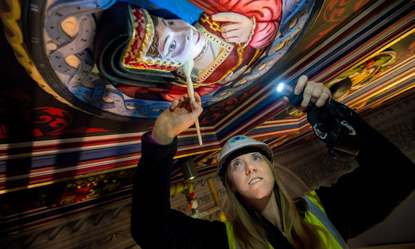 A woman in a hard hat and high vis inspecting a Stirling head on a ceiling at Stirling Castle