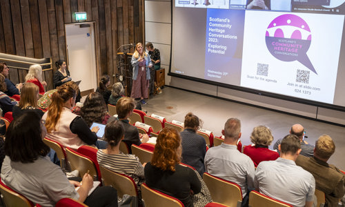 People seated in an auditorium watching a presentation 