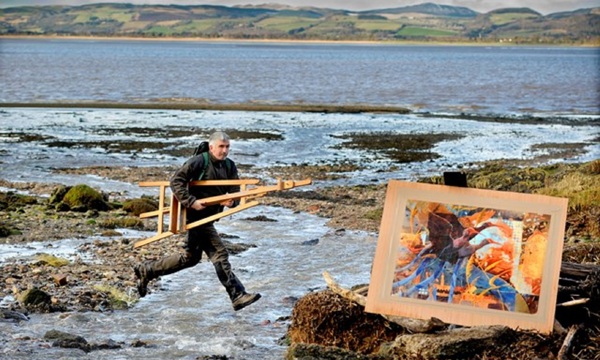 Artist Derek Robertson on a beach background with one of his artworks