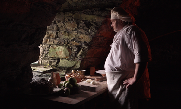 A chef with chopped up ingredients looking out a window