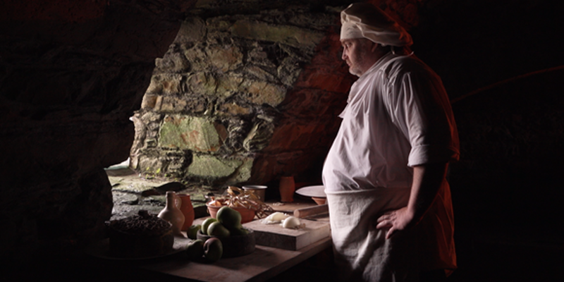 A chef with chopped up ingredients looking out a window
