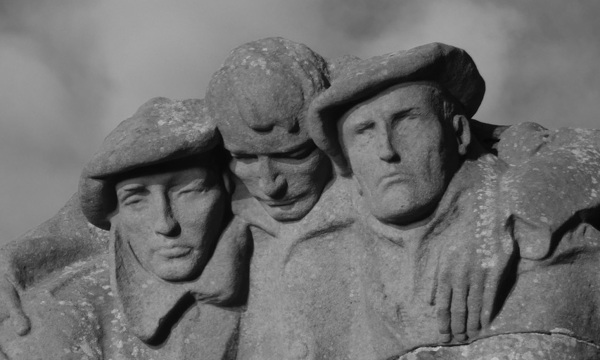 The statue of the Oban war memorial with a cloudy sky shown in black and white 