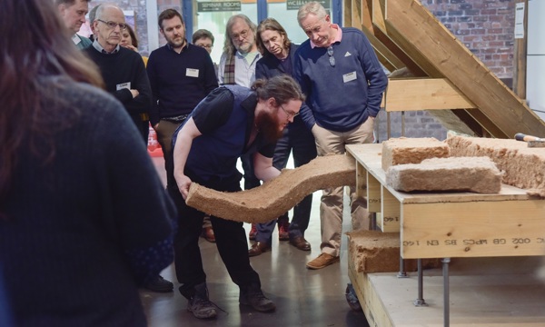 A group of people being shown traditional skills by an expert