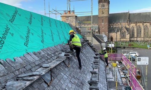 Two roofers working on a building next to Dunblane Cathedral