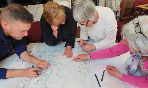 Four people leaning over a table with a map on it 