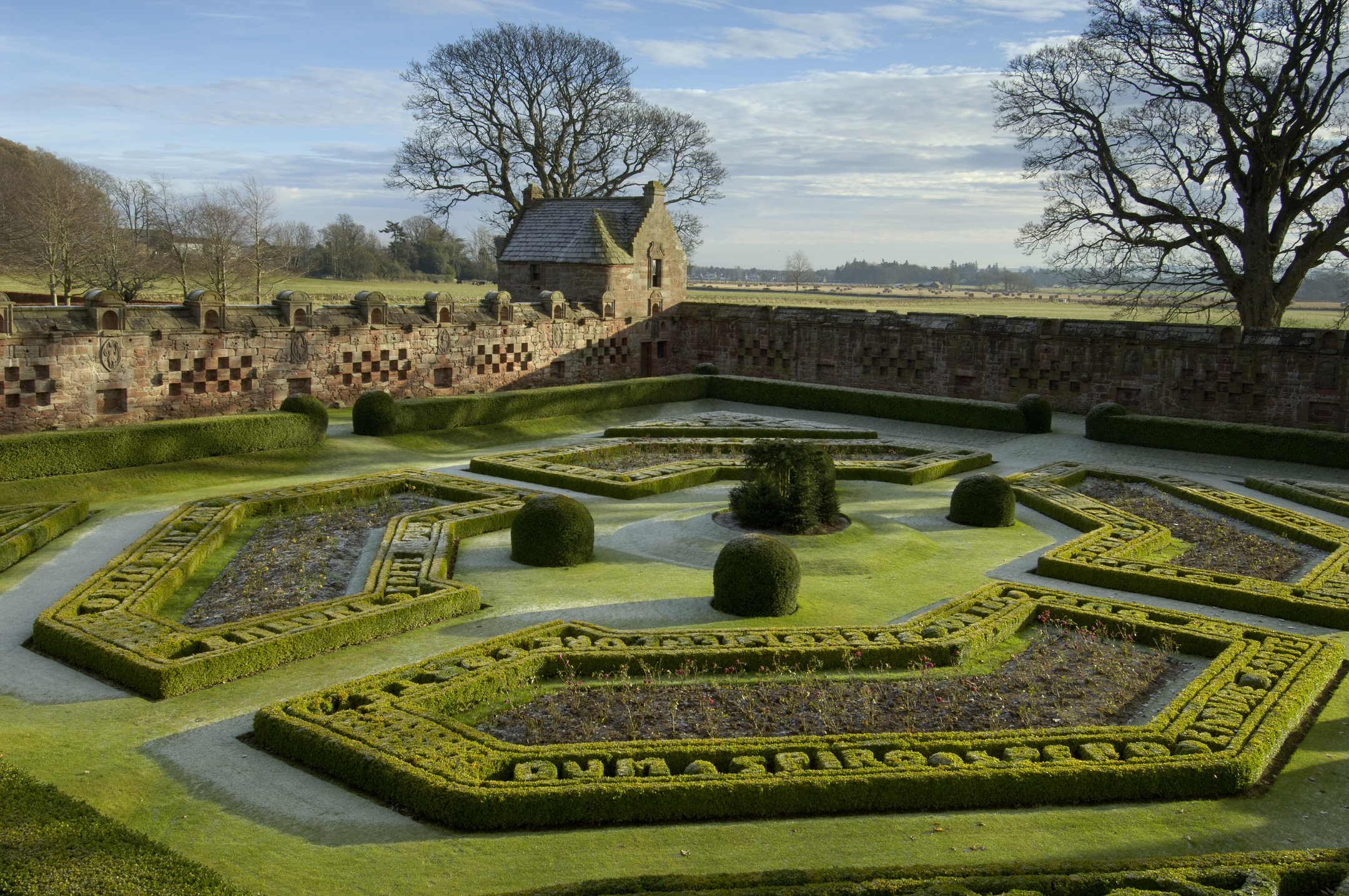 Frost or dew on the grass in an ornate and unique castle garden. Flower beds are laid out in a formal style.