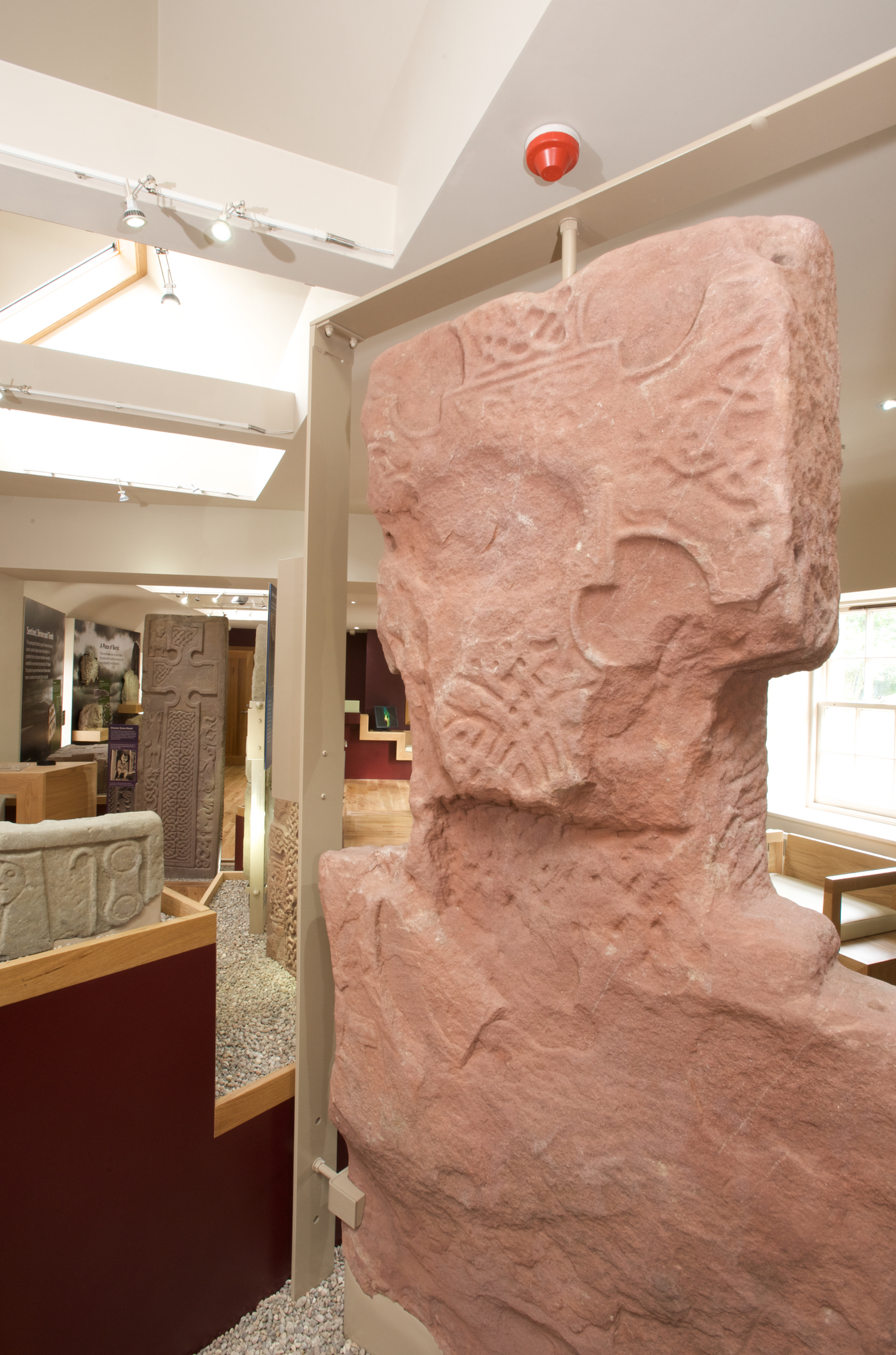 Detail of a weathered Pictish carved stone with interlace patterns and symbol motifs, mounted upright within the museum.
