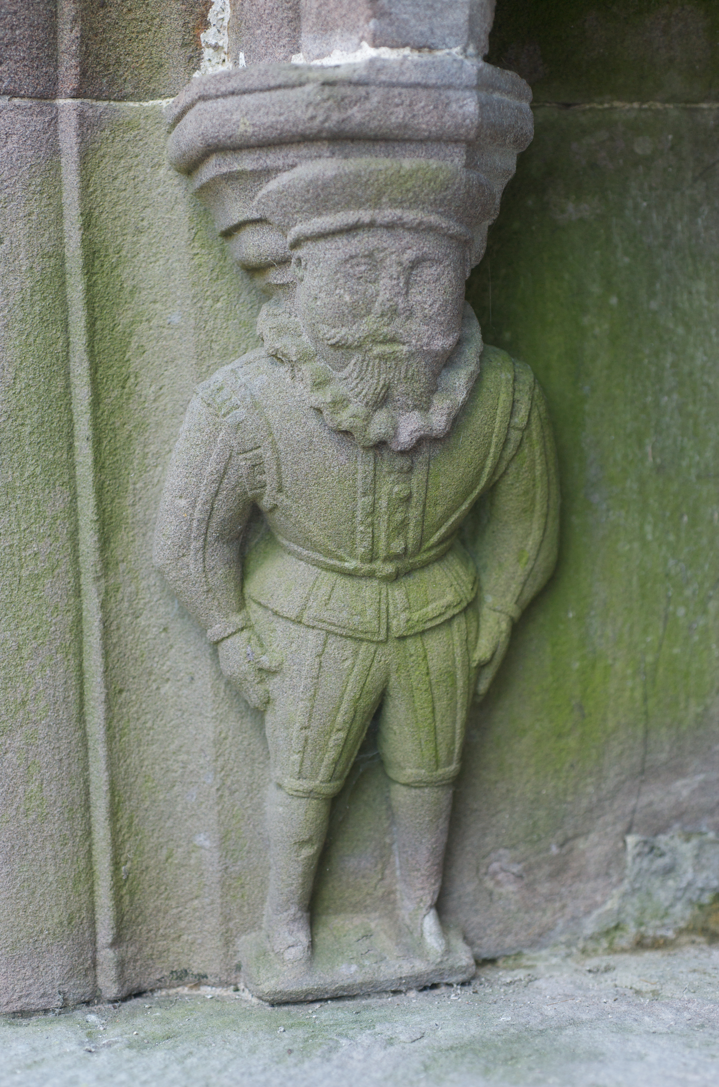 A small but ornate stone carving on a lord's tomb, It depicts the man in historic dress including a ruff. 
