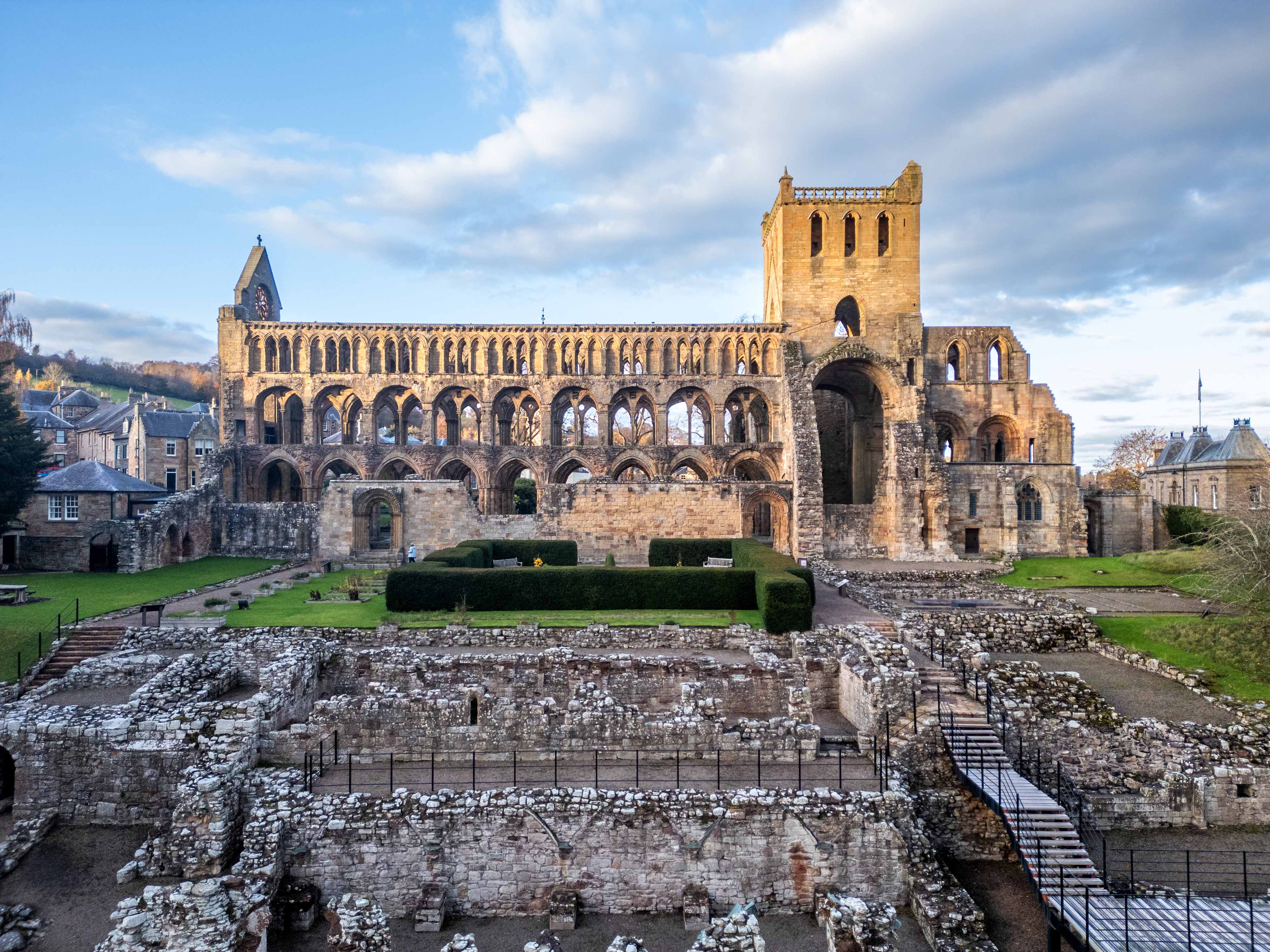 A large, sandstone abbey featuring many empty archways where windows once would have been