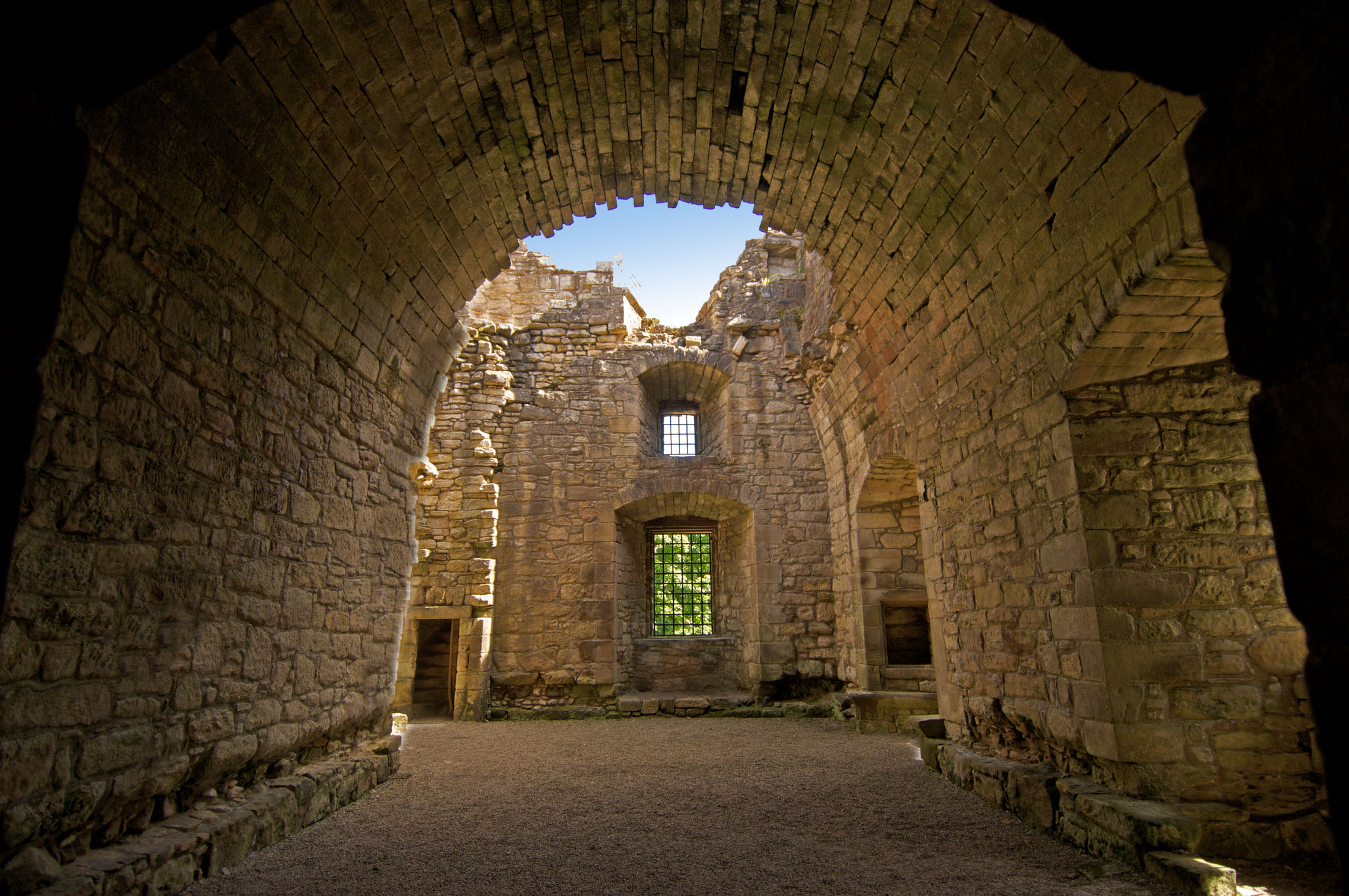 Interior view of vaulted stone ceiling and arched windows in castle ruins.
