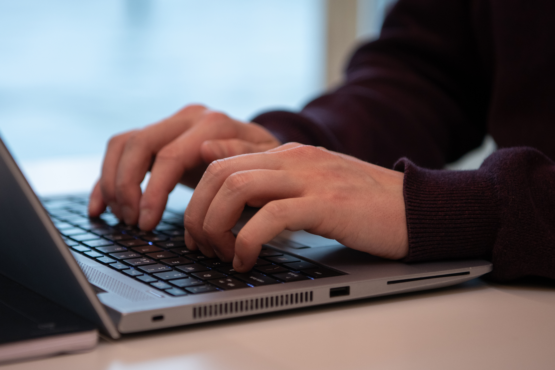 Hands typing on laptop keyboard