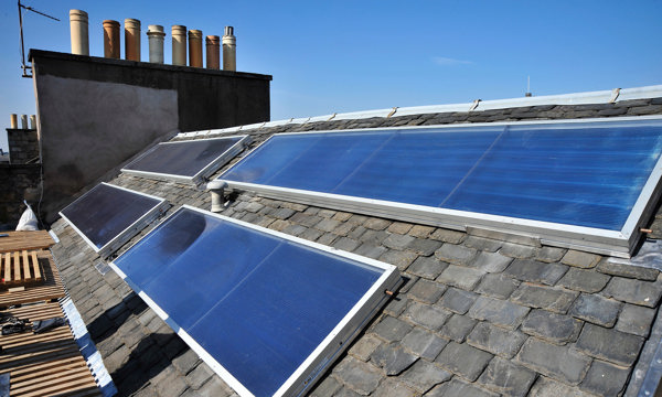 A roof with multiple chimneys and solar panels