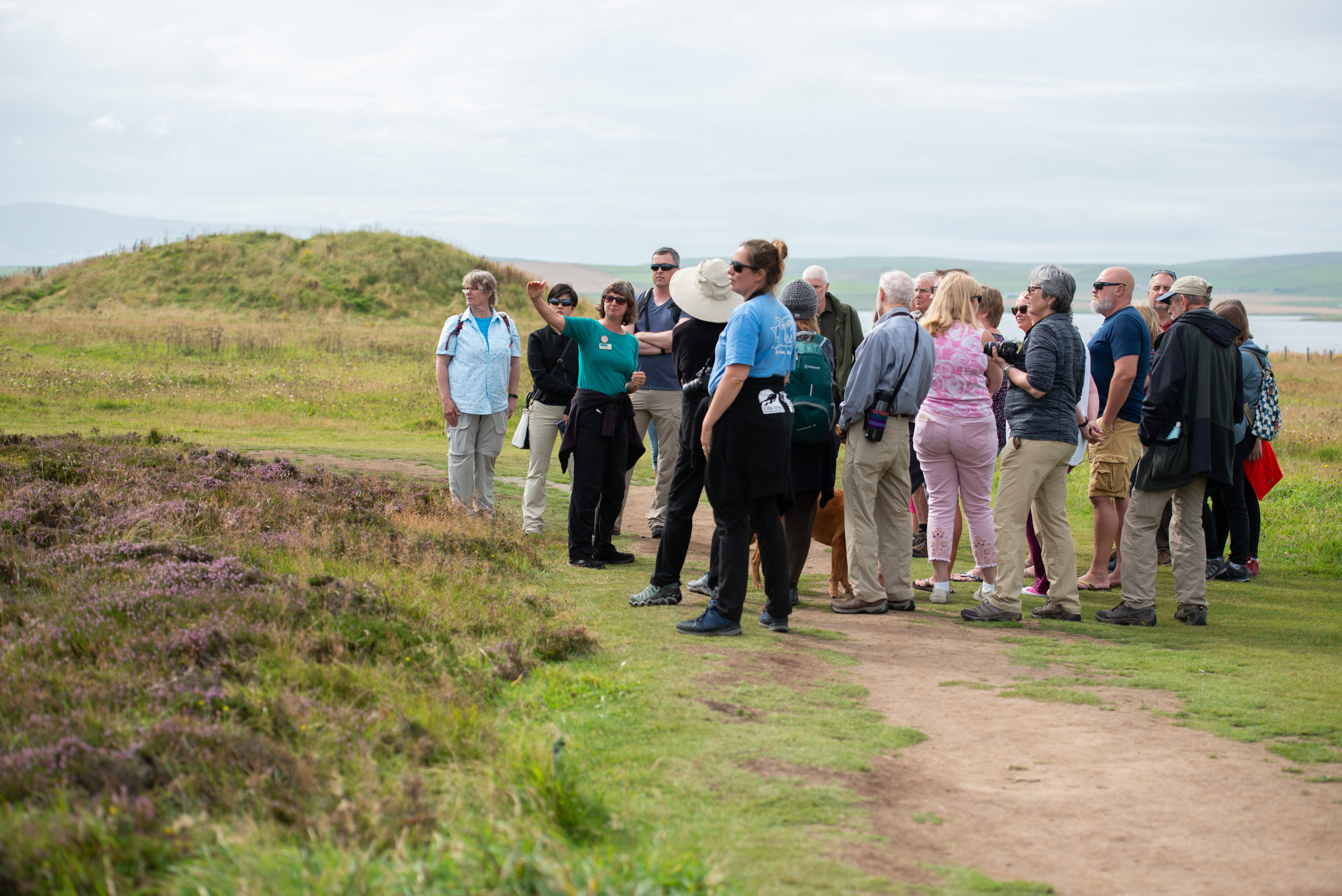 A group of visitors taking a guided walk around a stone circle. 