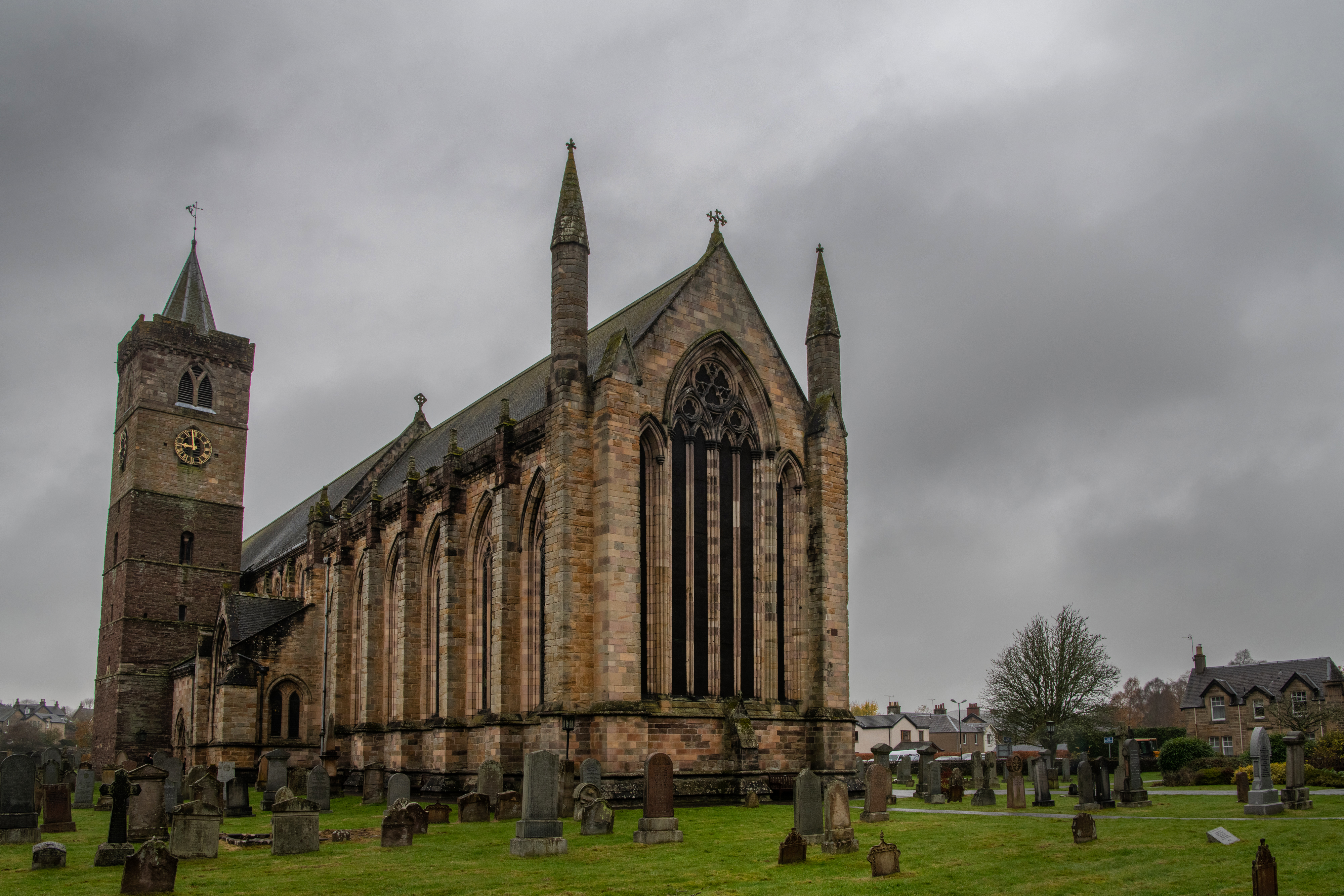 Cathedral building, tower, and graveyard on a gloomy day under grey skies.