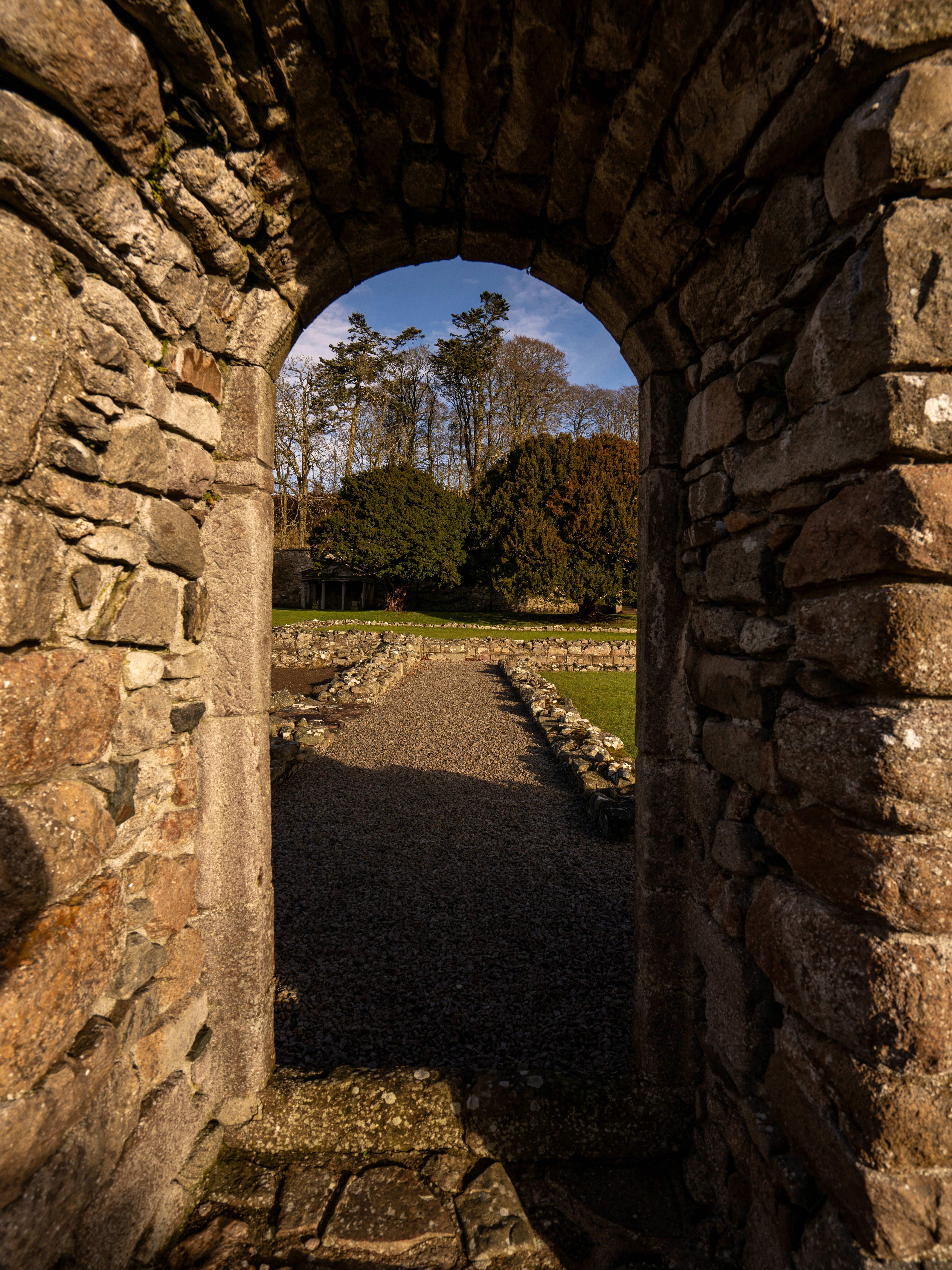 View of path and trees through an old stone archway.
