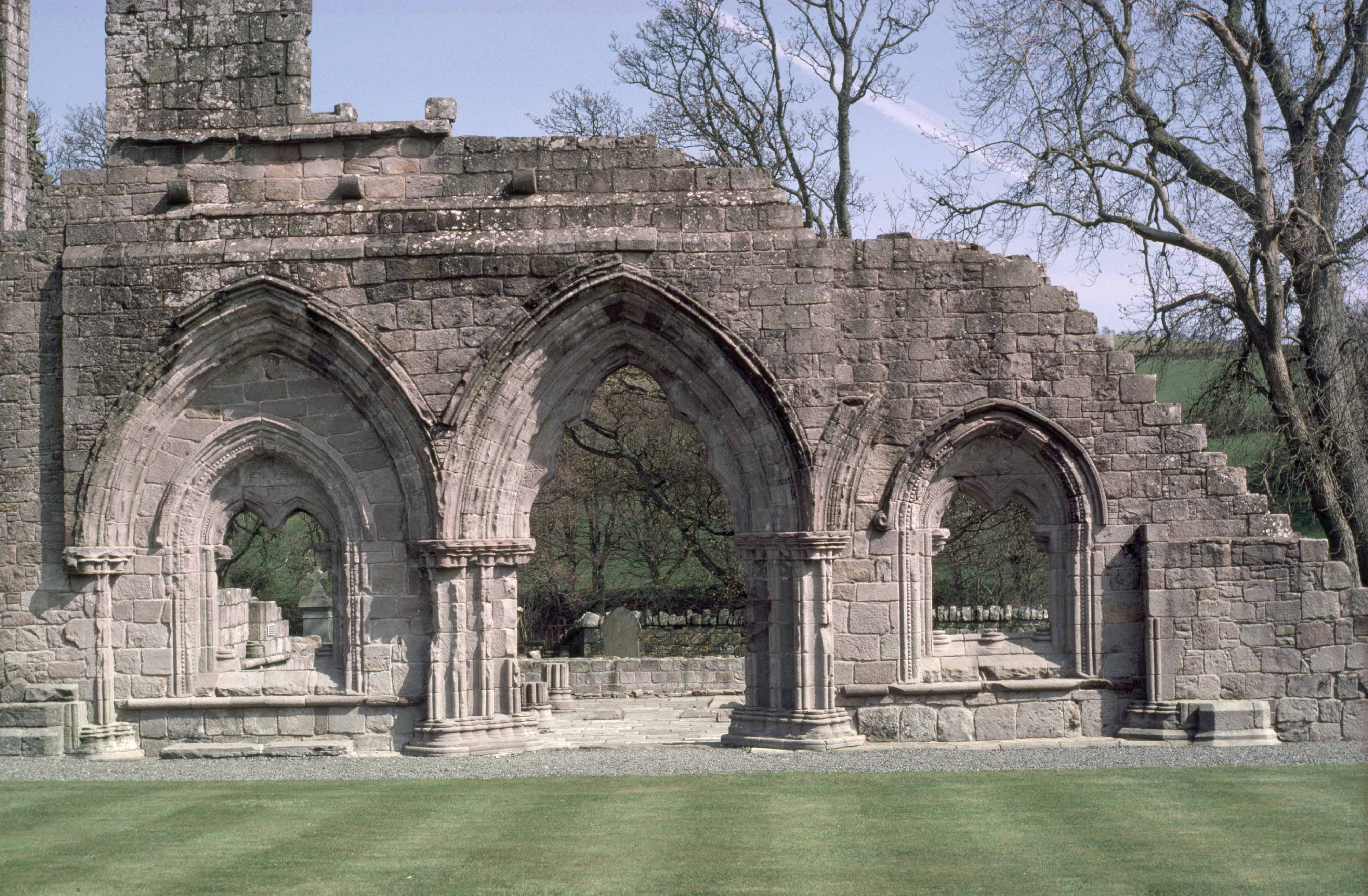 A historic stone abbey wall in ruins, with archways 