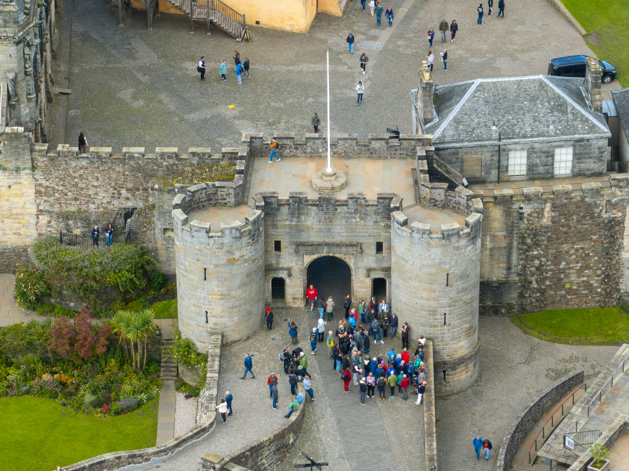 An aerial photo of a group of visitors mingling around the entrance to Stirling Castle, which consists of a large, formidable stone gatehouse.