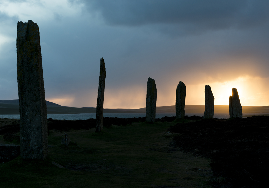 The ancient standing stones at the Ring of Brodgar are silhouetted by a sunset