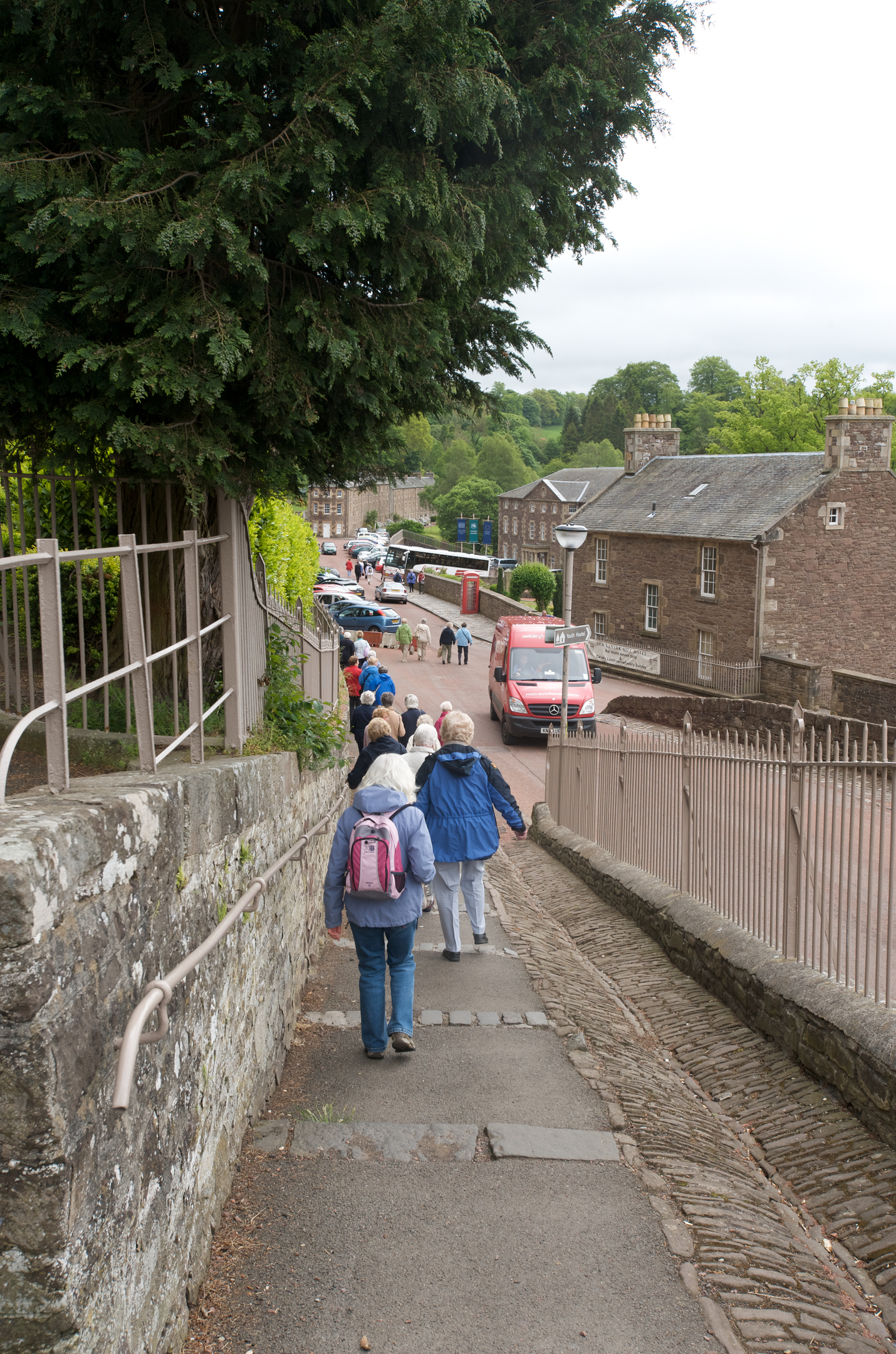 A line of schoolchildren walking down a slope towards 18th century stone buildings