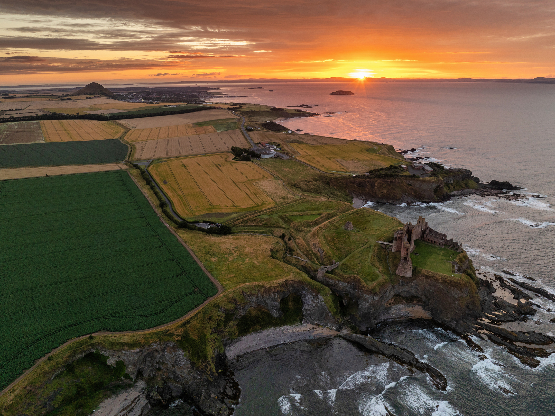 Aerial view of the distinctive coastline at Tantallon with the sun setting in the distance
