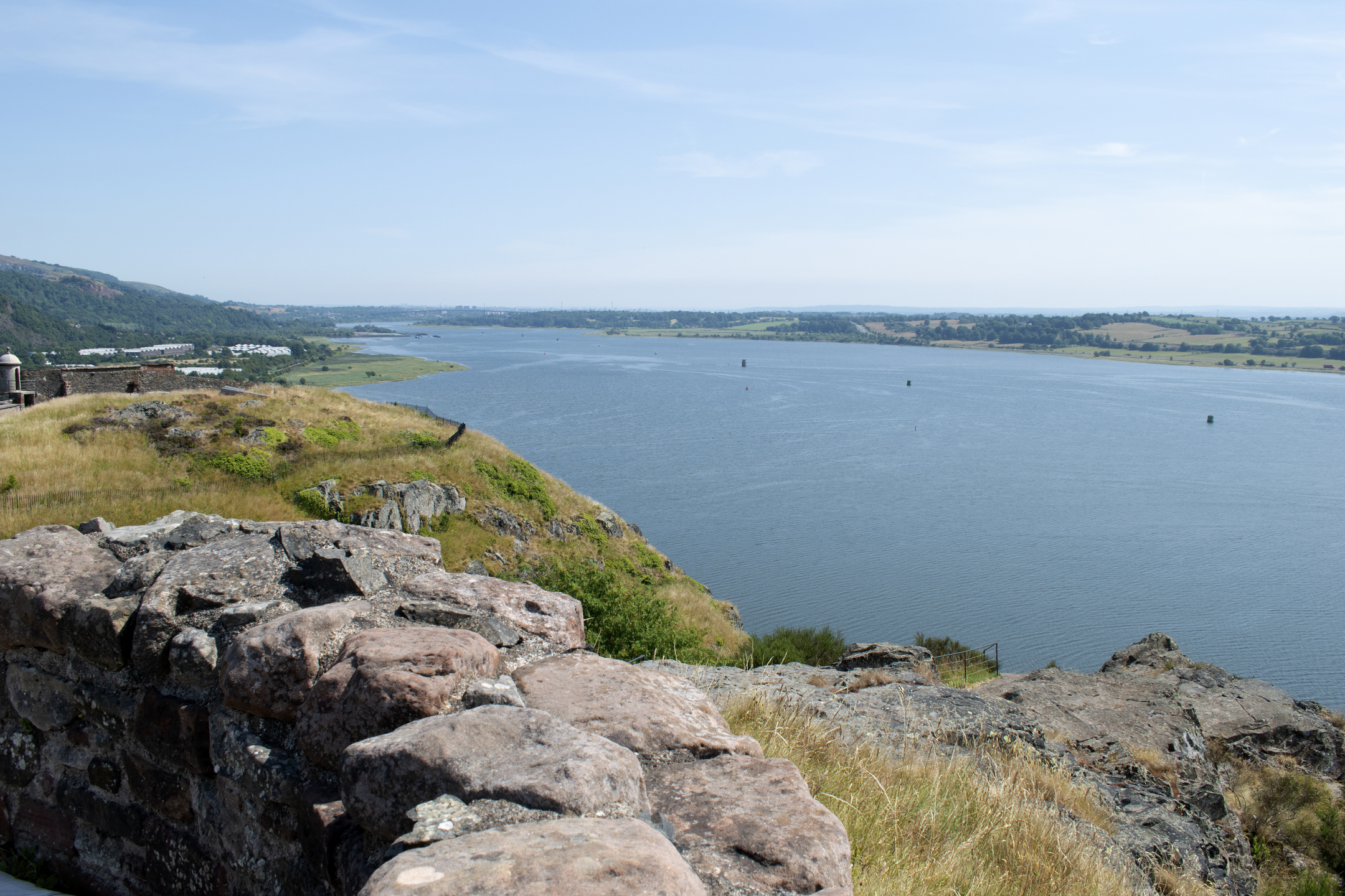 A panoramic view of the River Clyde, surrounding fields, and distant hills seen from atop a rocky viewpoint.