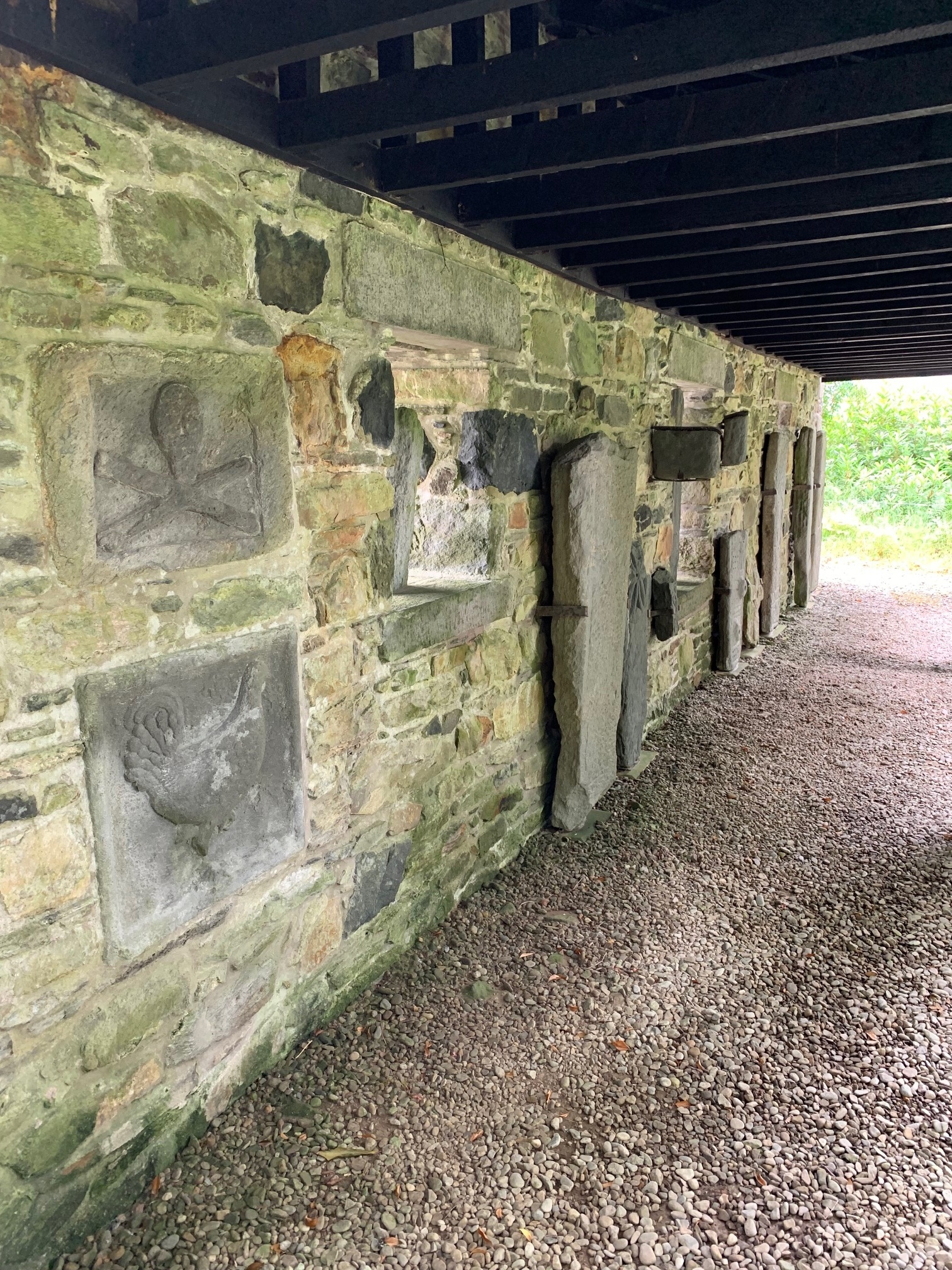 Scultred stones next to a wall and a gravel walkway.