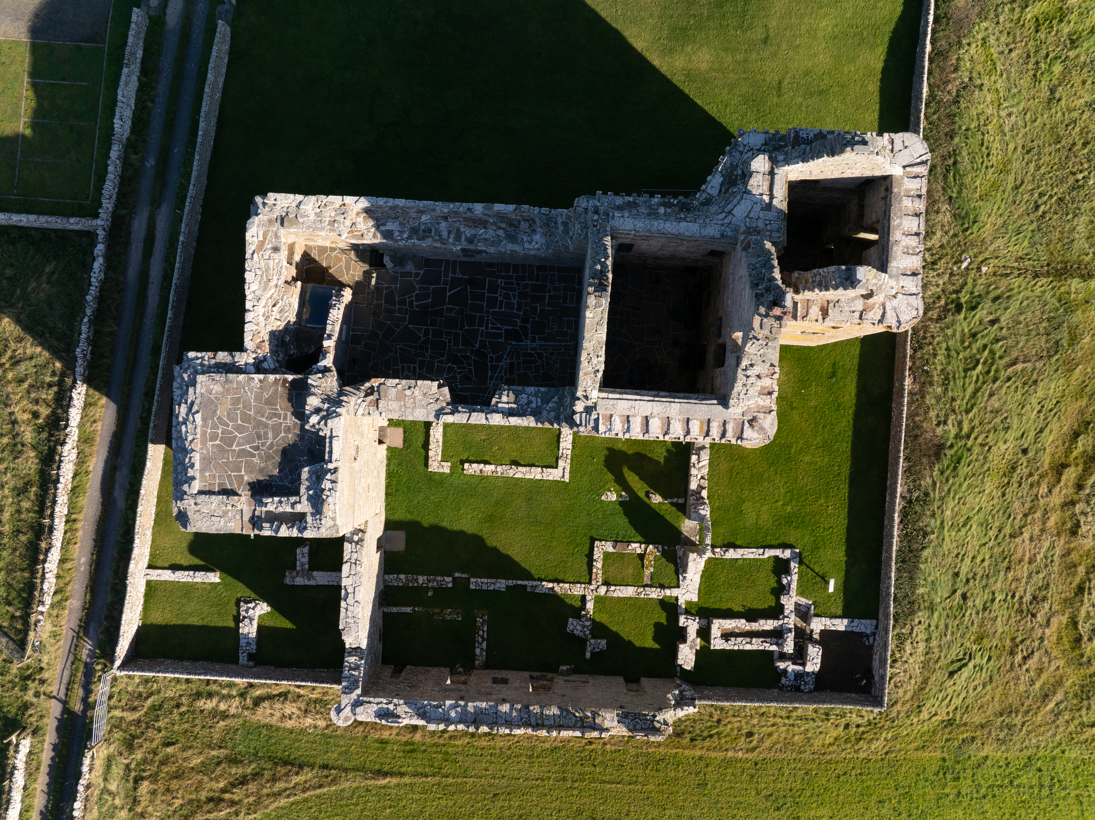 Top-down aerial view showing the full footprint of Noltland Castle, including walls, interior partitions, and grassy surrounding grounds.