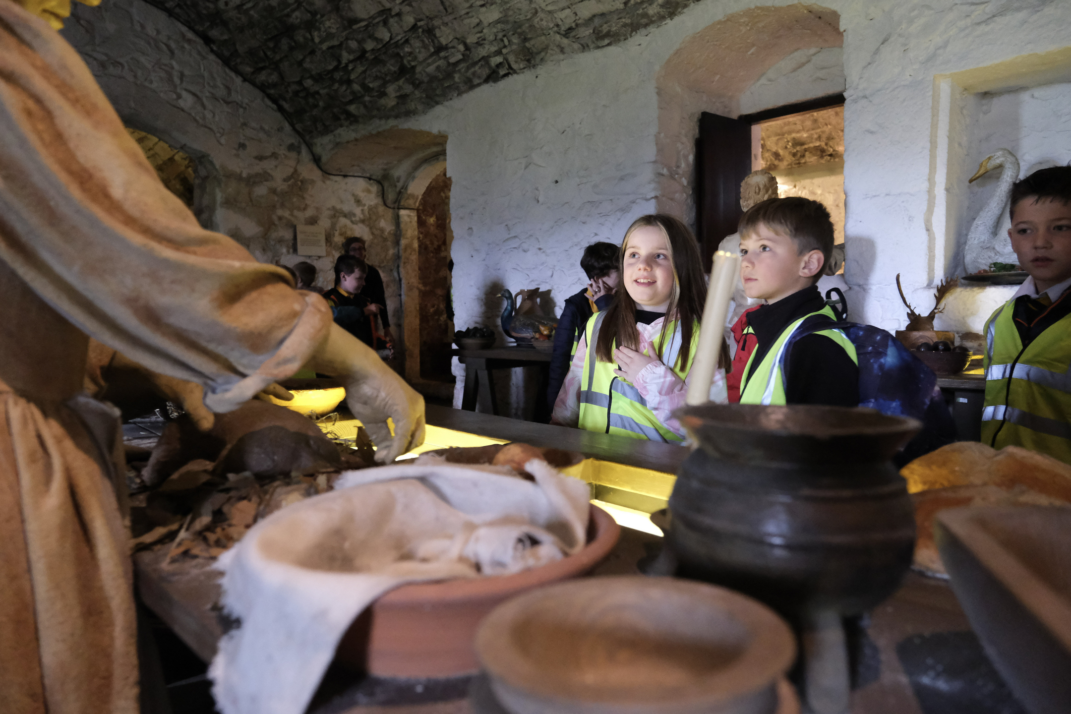 School pupils look towards display with costumed figure preparing food