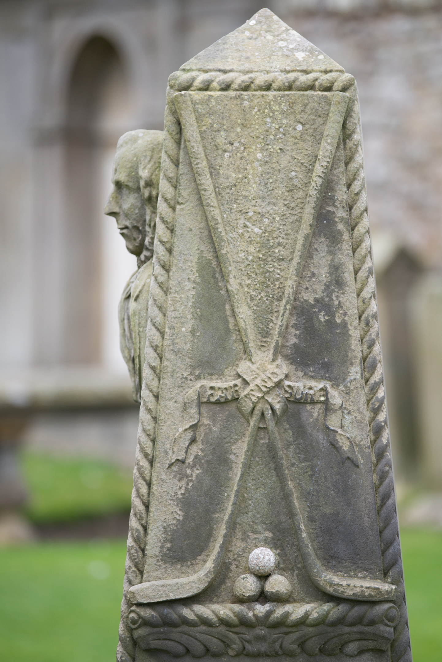 A close up shot of a carving of two golf clubs and a stack of three golf balls on a tombstone at St Andrews Cathedral