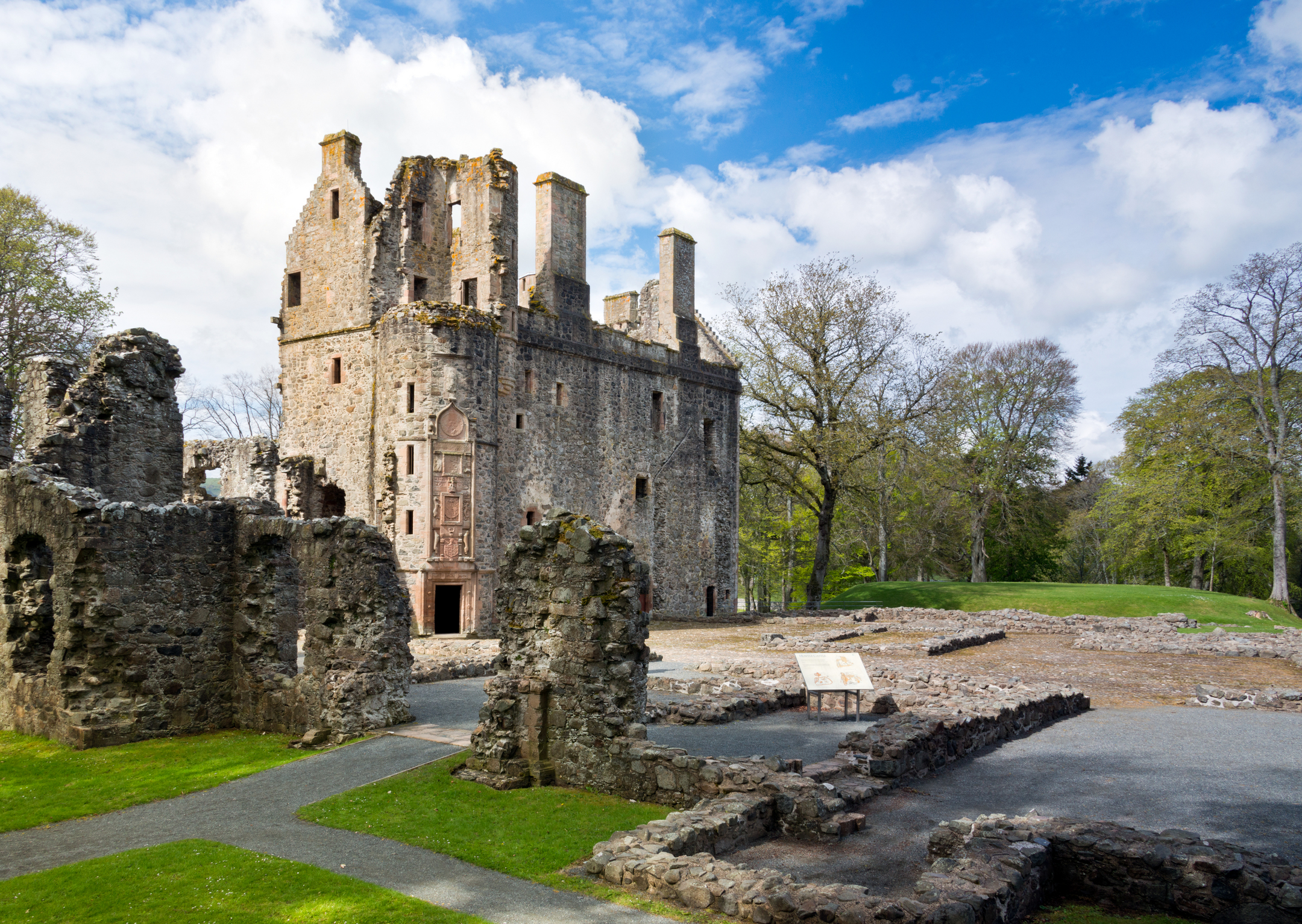 View of castle ruins with mostly levelled sections in the foreground and a portion in good condition further away