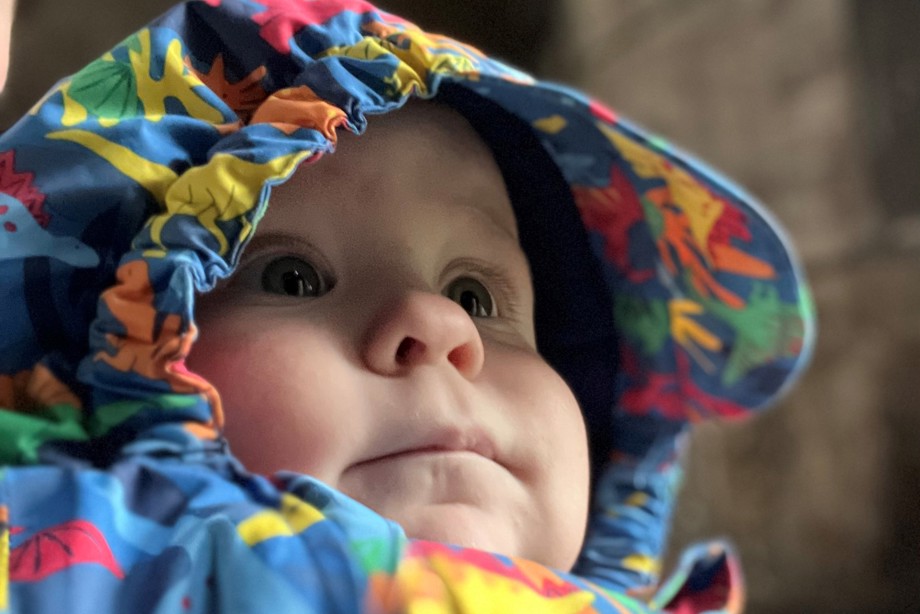 A baby in a rain jacket is looking at surroundings in Doune Castle
