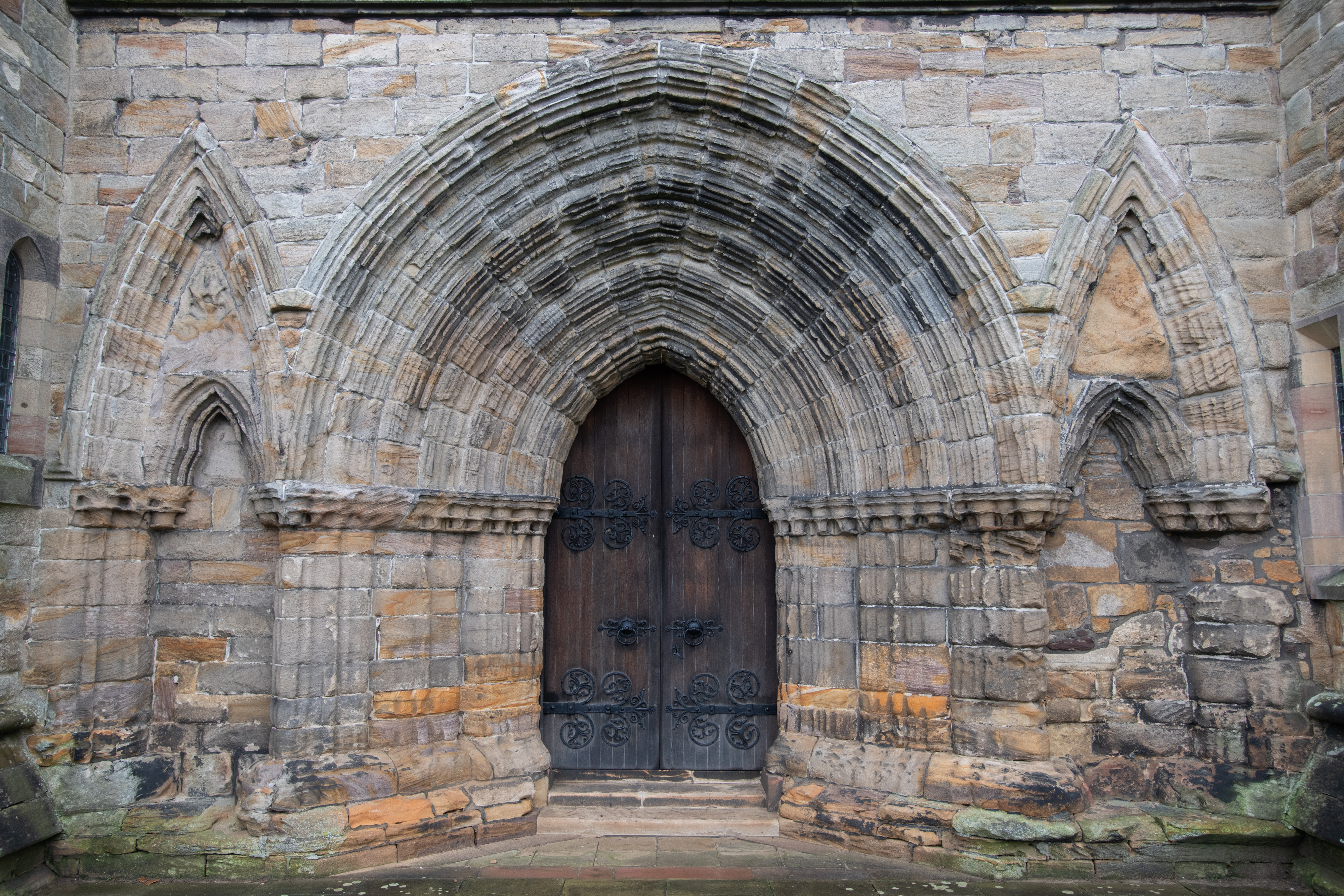 Wooden door set in an ornately carved stone wall.