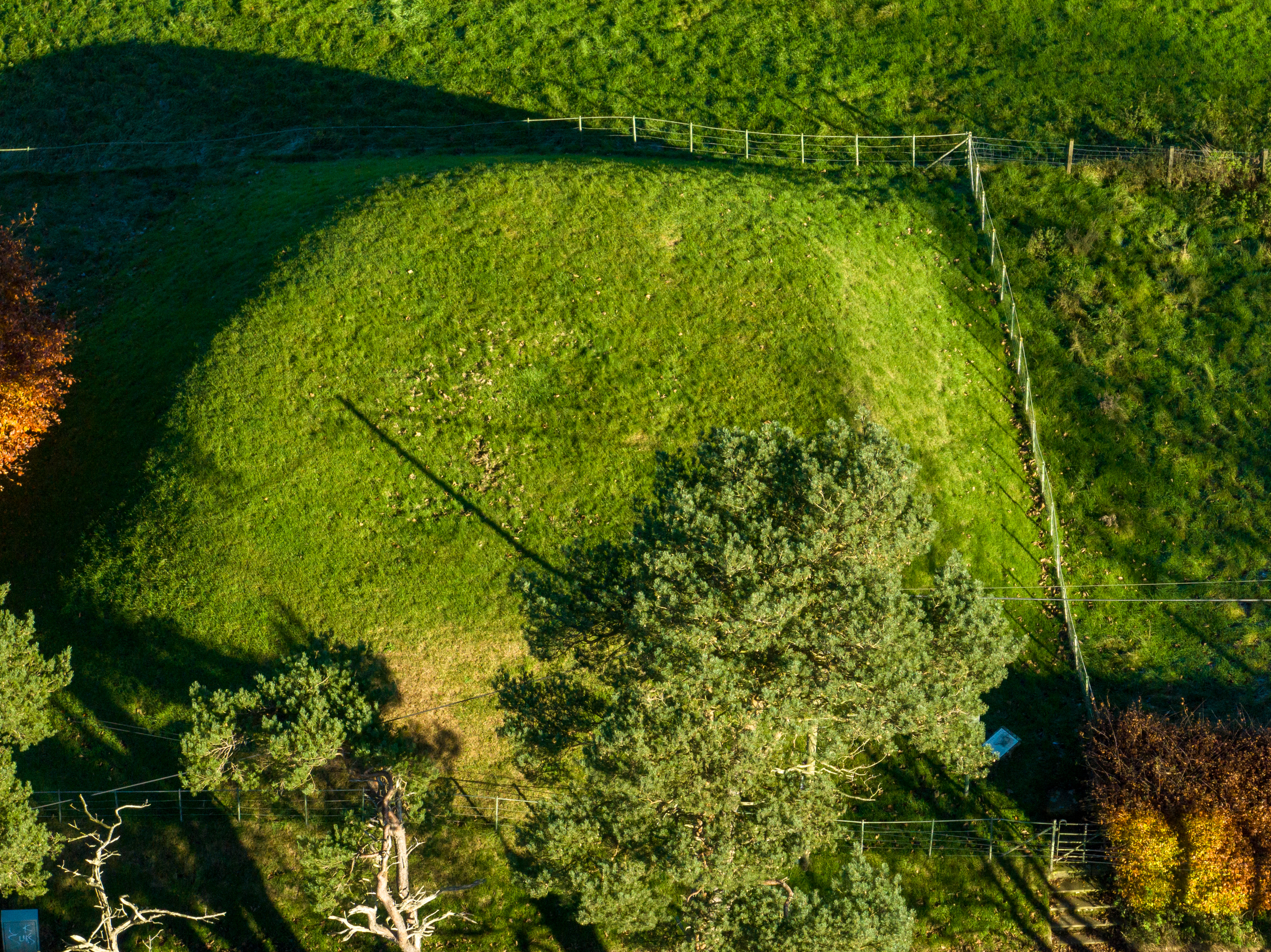 A drone photo taken directly above a manmade earth mound covered in short grass