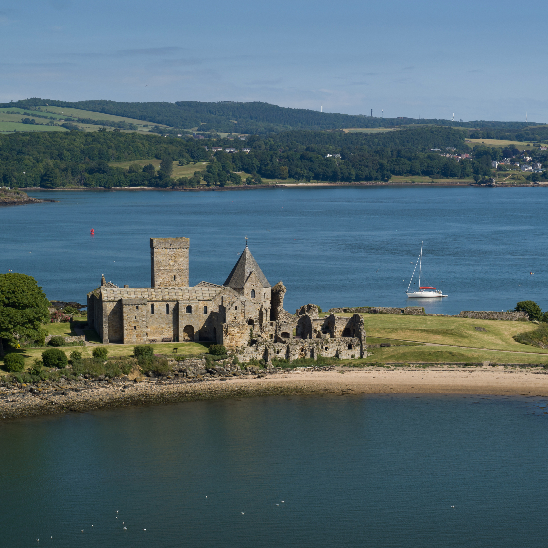 A historic stone abbey on an island, with a small boat nearby