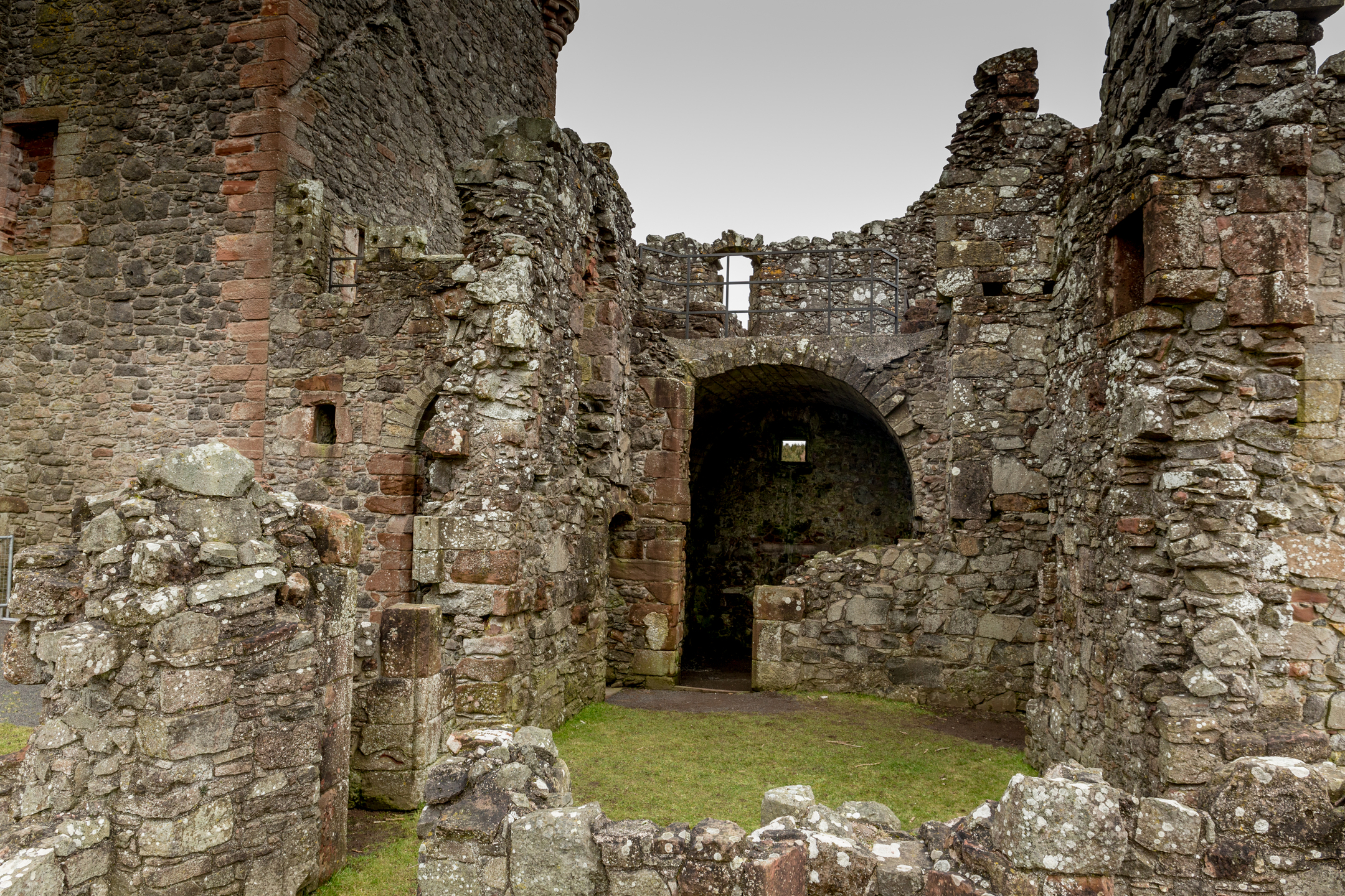 Inside the ruined courtyard of Balvaird Castle, showing weathered stone walls, archways, and an open grassy floor 