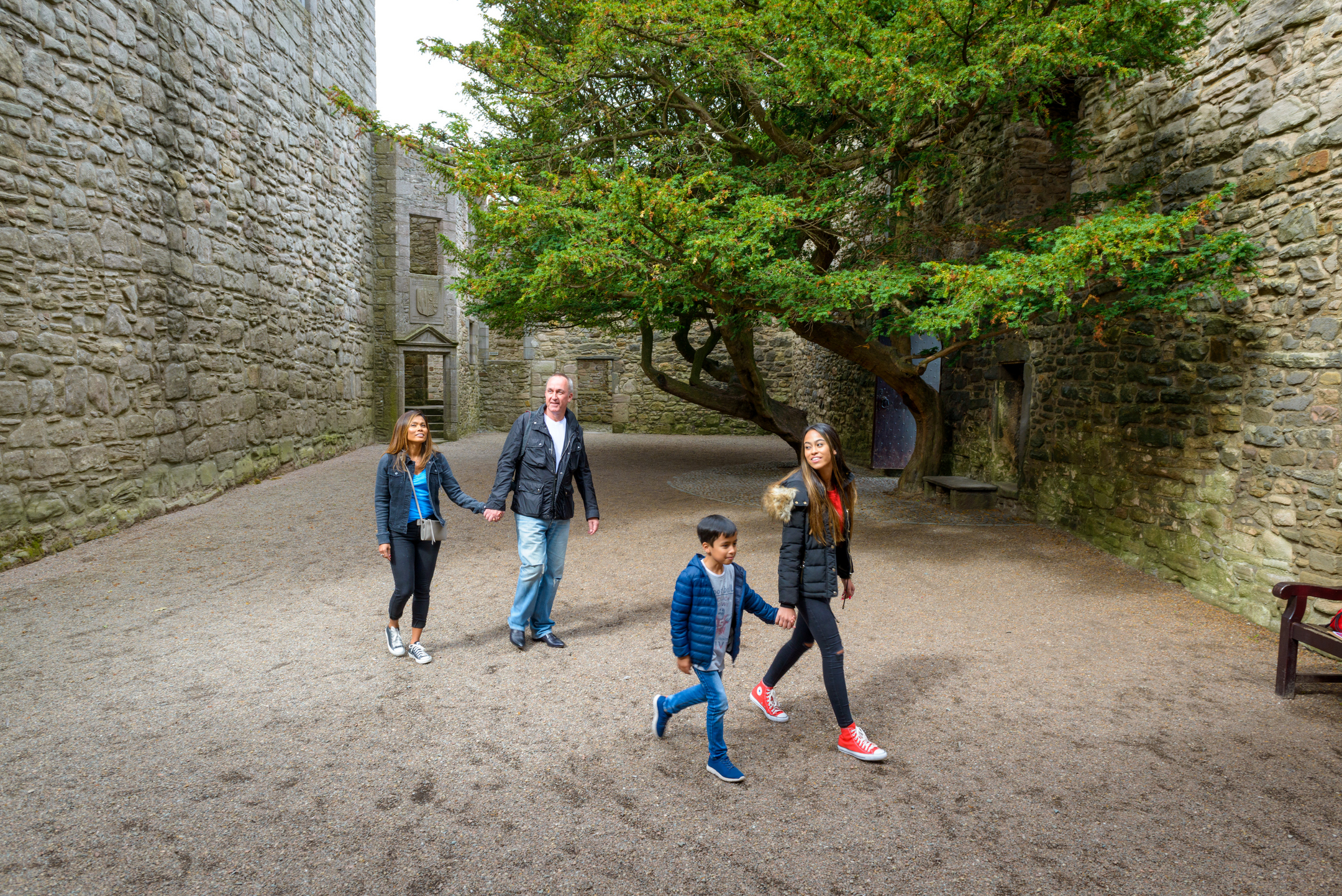 A family make their way through the courtyard at a ruined castle.