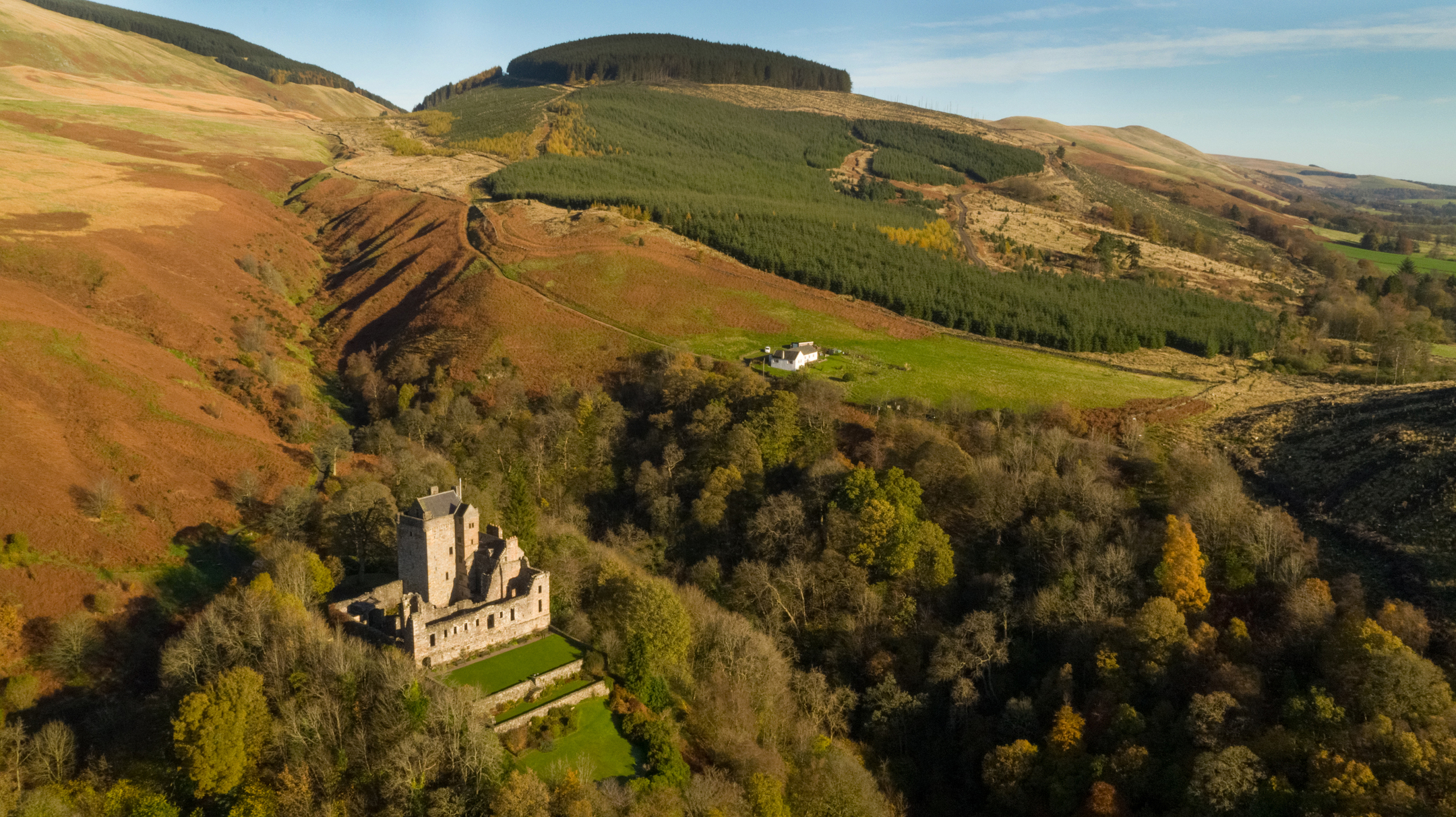 Angles UAV image showing Castle Campbell in the Dollar Glen surrounded by trees on a golden day. 
