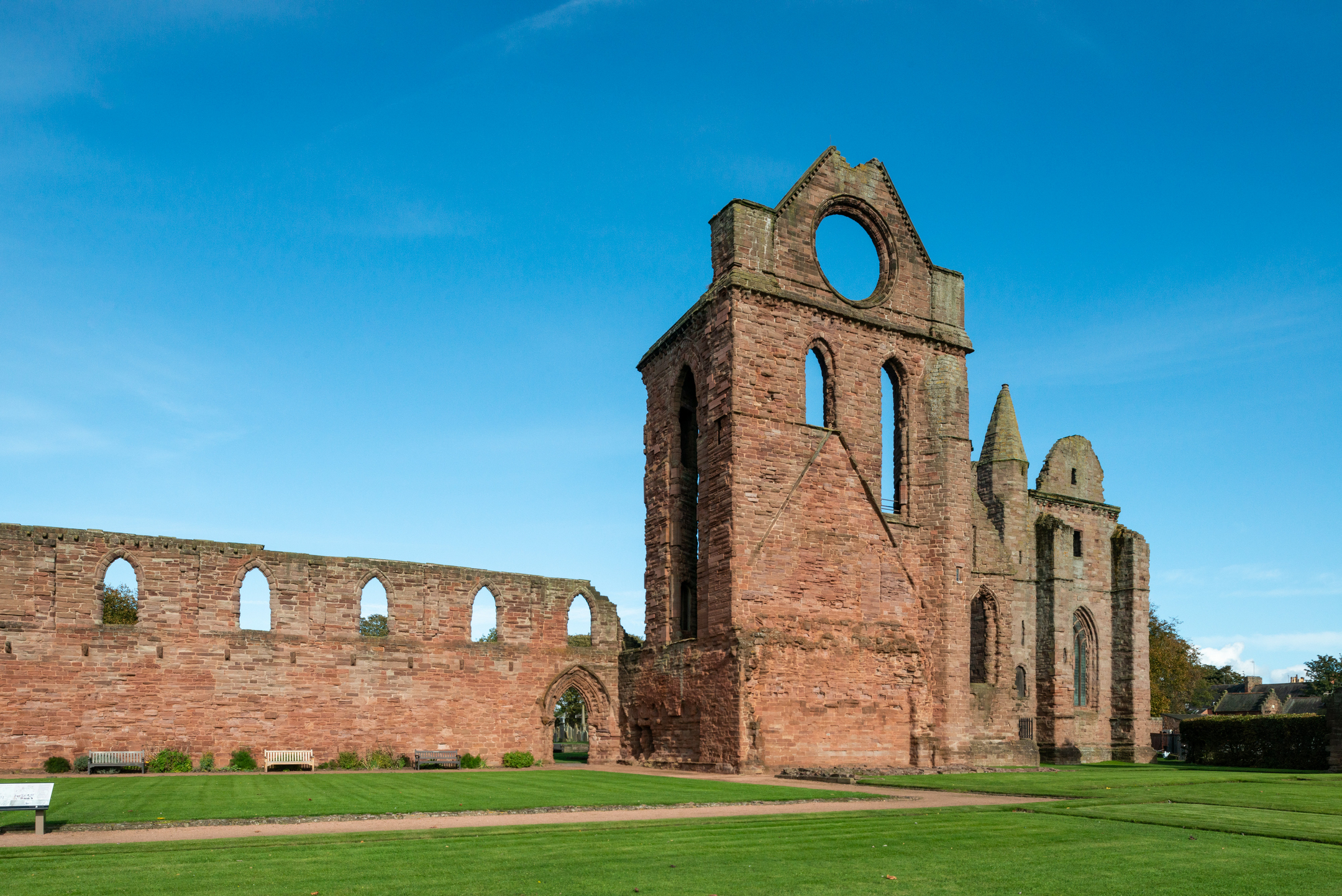 Single side of an abbey with grass in front and blue sky